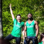 Two participants posing for a picture, the other one is raising her hand