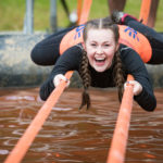A woman lies across two straps smiling