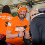 Man in orange top and hat gives thumbs up