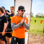 Man in orange top clapping in awe